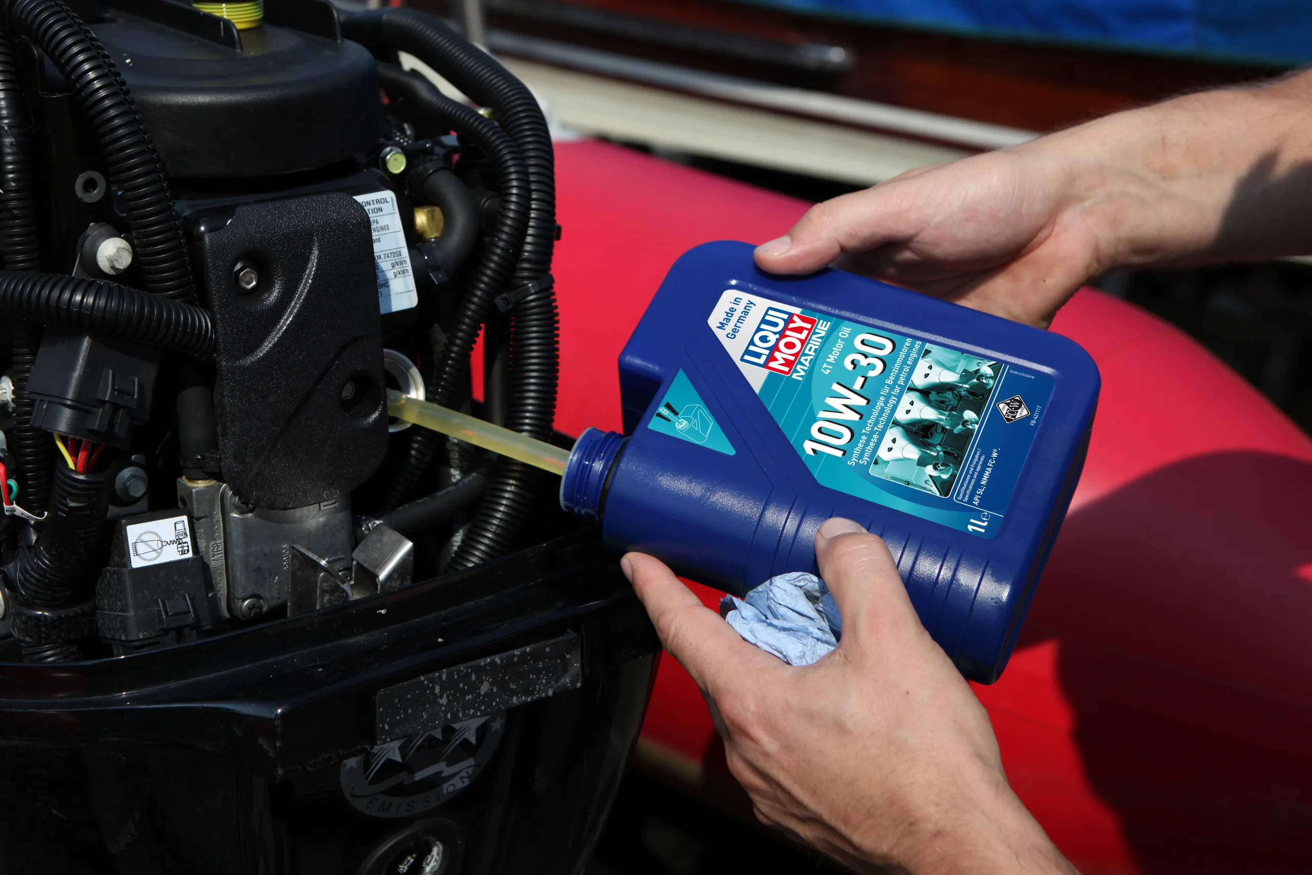Mann befüllt einen Außenbordmotor mit Motoröl von Liqui Moly